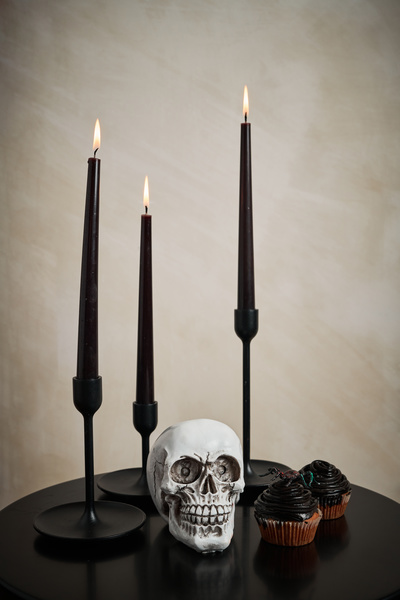 Skull Is on Table Next to Candles and Cupcakes